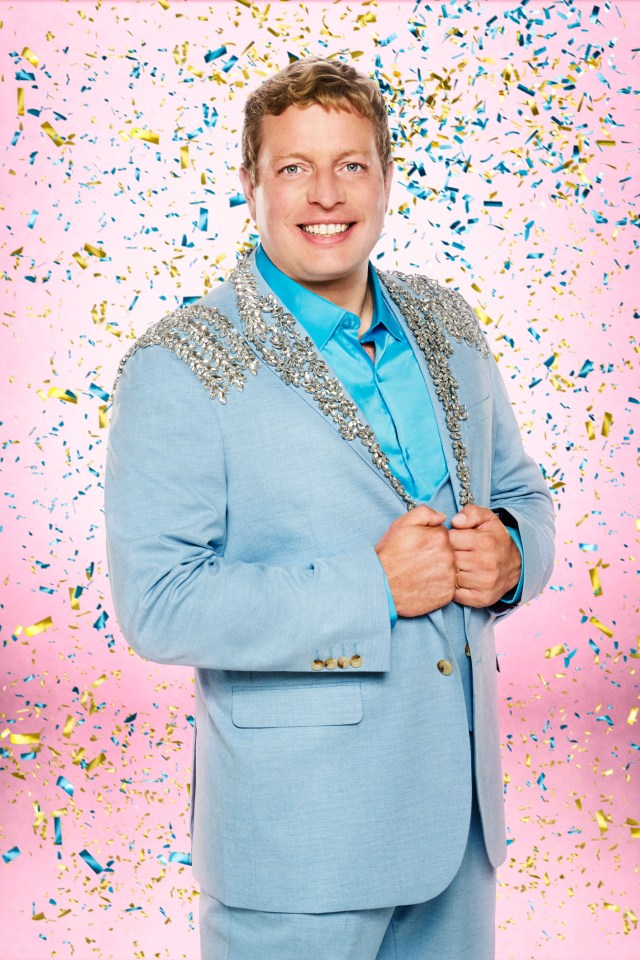 Tom Skinner in a light blue suit with sparkly silver embellishments and a blue shirt, smiling at the camera with confetti falling around him.