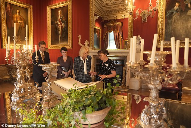 Lord Burlington (left), and Queen's Reading Room CEO Vicki Perrin (second left), watch as Queen Camilla views a selection of artefacts from the Jane Austen House museum