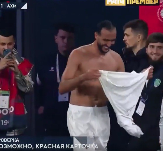 Shirtless soccer player pulling off his white shorts.