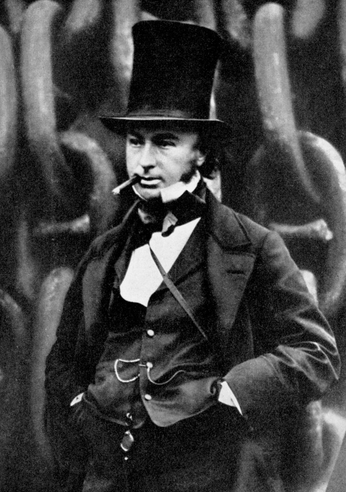 Isambard Kingdom Brunel in a top hat, with a cigar in his mouth, standing in front of large chains.