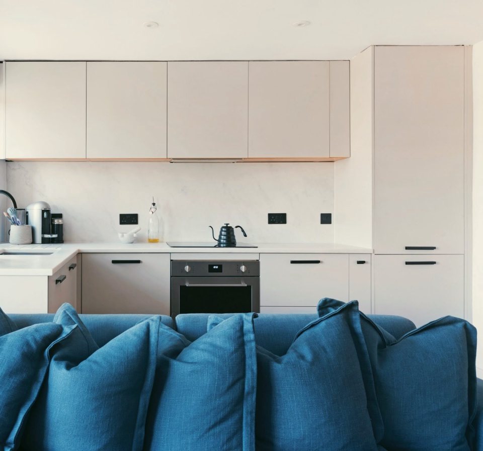 Modern kitchen and living room with blue sofa pillows.