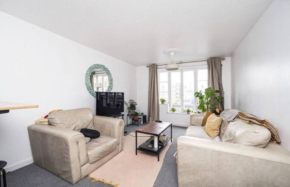 Living room with light beige leather sofas, coffee table, and large window.