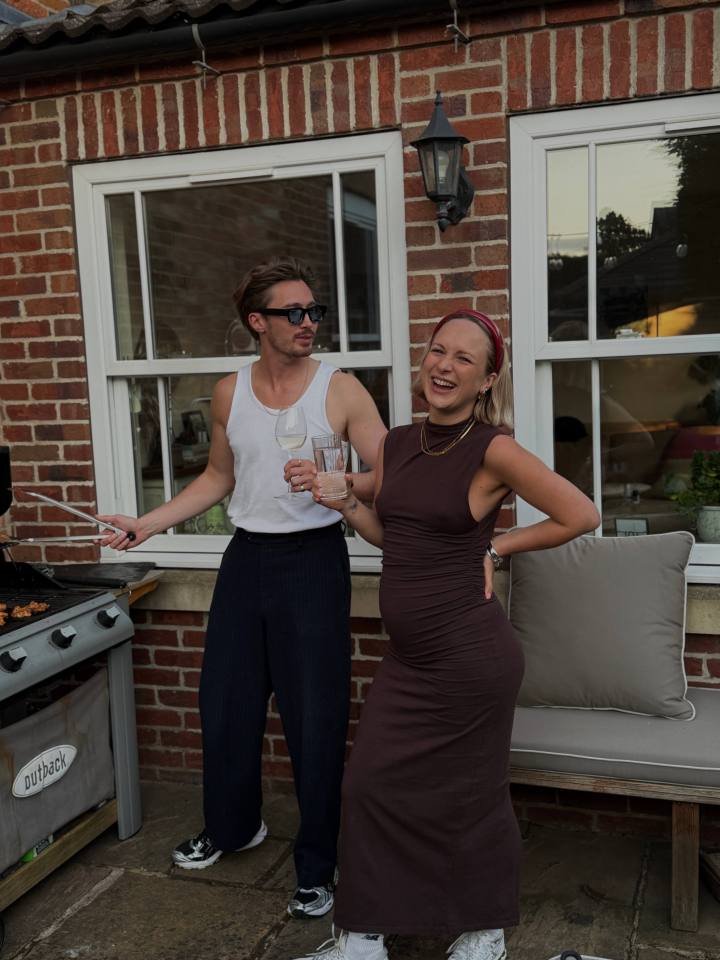 Couple grilling outdoors; one holds drinks.