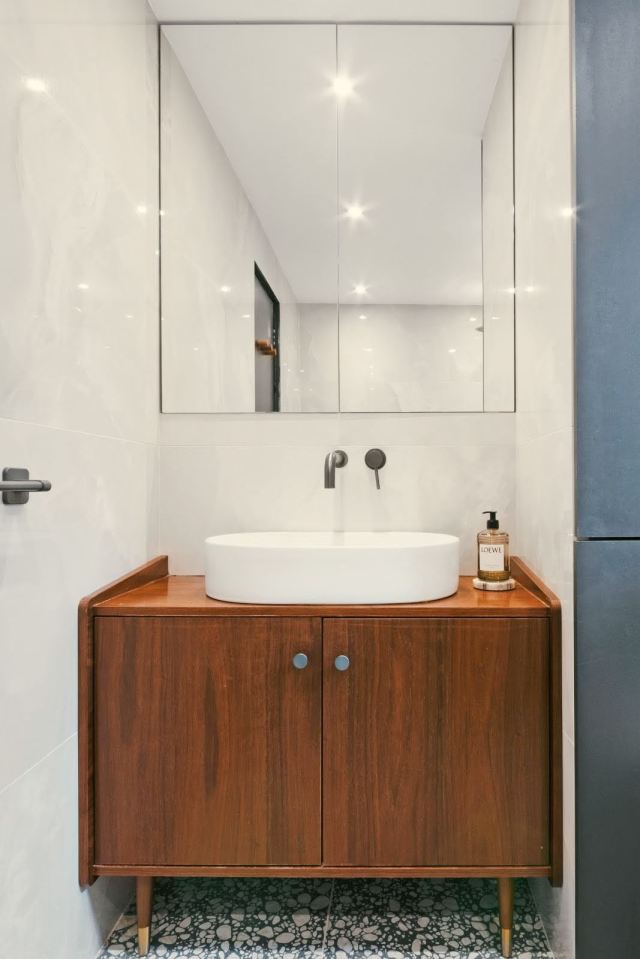 Modern bathroom vanity with a white sink and wooden cabinet.