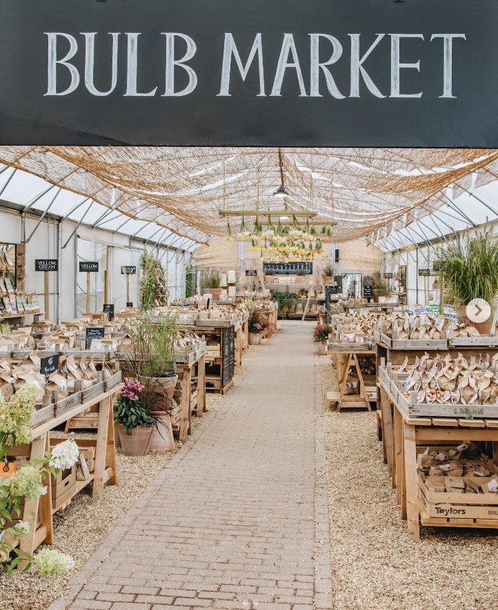 A "BULB MARKET" sign above a garden center aisle filled with bulbs and plants.