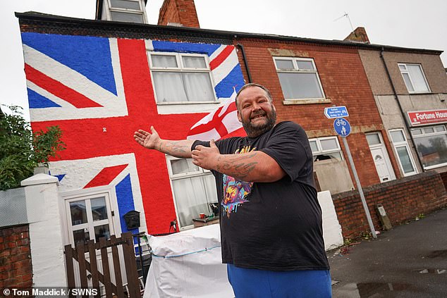 Simon Brocklehurst spent 12 hours plastering the huge flag on his four-bed terraced home, which has left locals fearful that property prices in the area will plummet