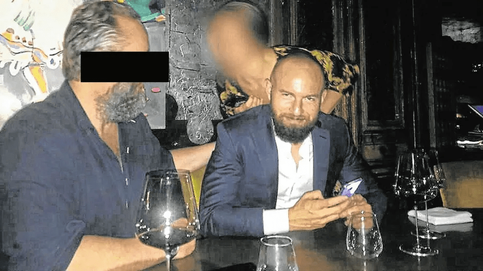 Two men with blurred faces sit at a table with glasses.