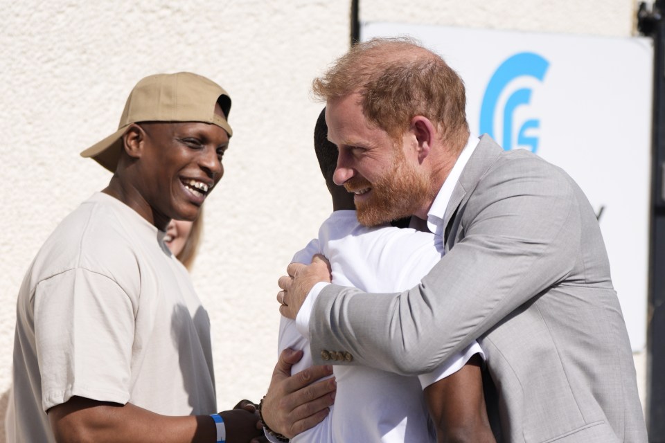 Prince Harry hugging a young man at a donation announcement.