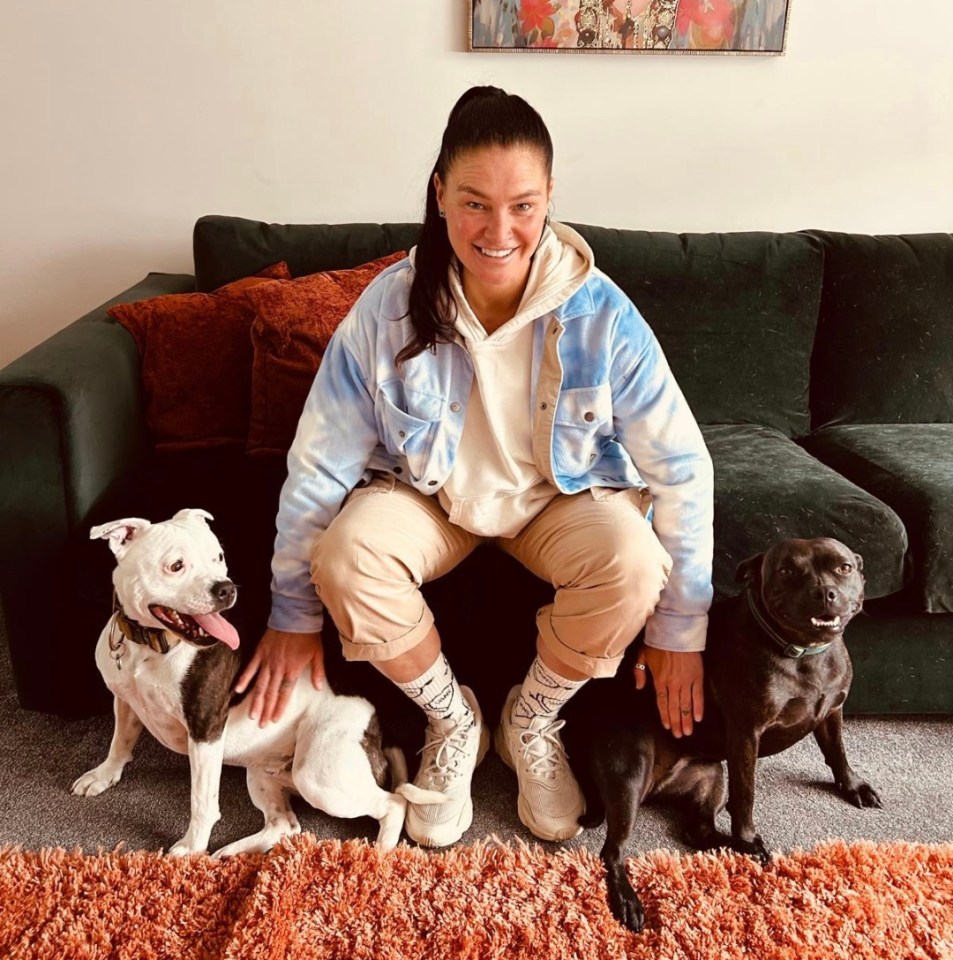 Woman sitting on a couch with two dogs.
