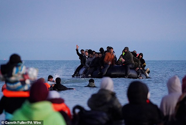 A small boat carrying people thought to be migrants arrives to collect more people in Gravelines, France, on Friday