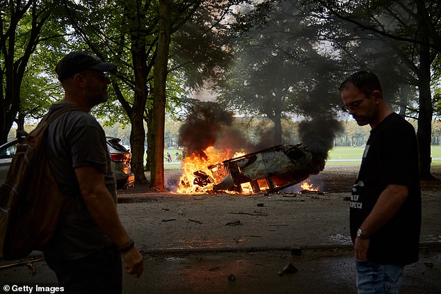 A police car burns after being torched by the far right protestors in The Hague