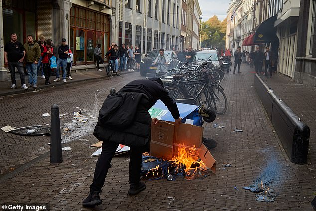 A far-right protester burns cardboard outside the D66 (centrist liberal) party office, where protesters had earlier smashed windows