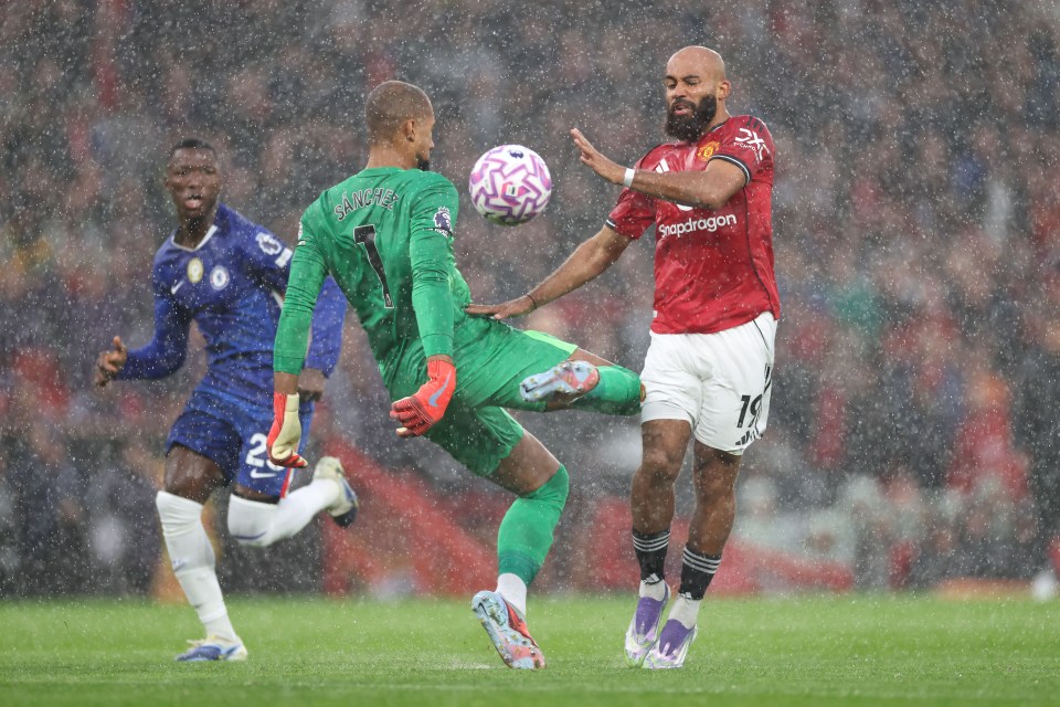 Robert Sanchez of Chelsea fouls Bryan Mbeumo of Manchester United in the rain.