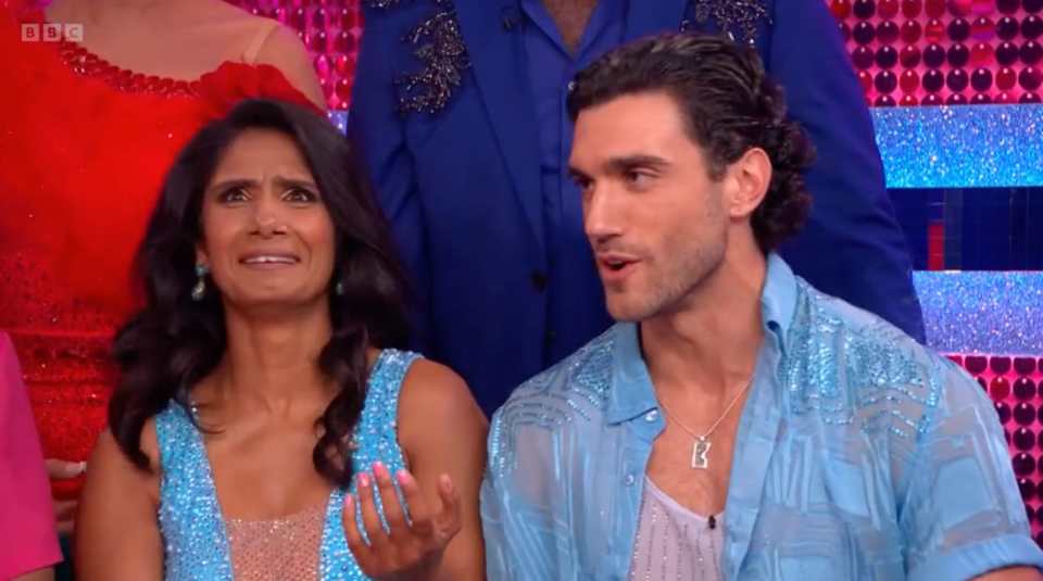 A woman crying and a man talking, both in blue, sequined outfits.