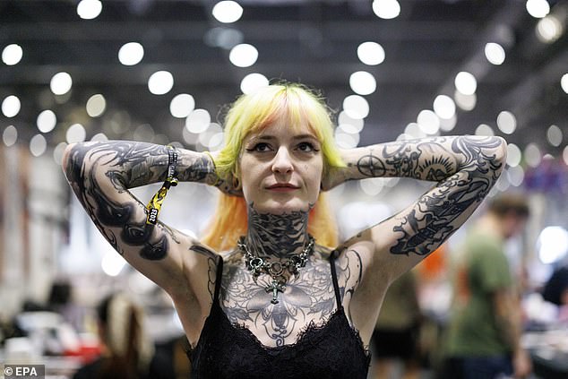 A woman poses at the three-day event at The Excel, showing off her intricate tattoos