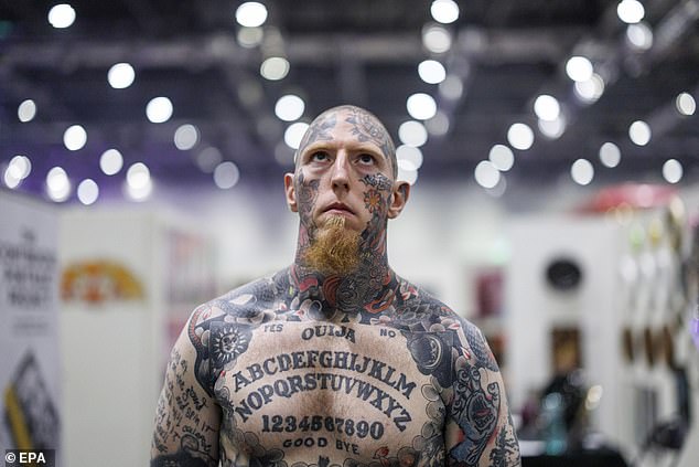 A visitor with a ouija board tattood across his chest poses for a picture at the three-day event