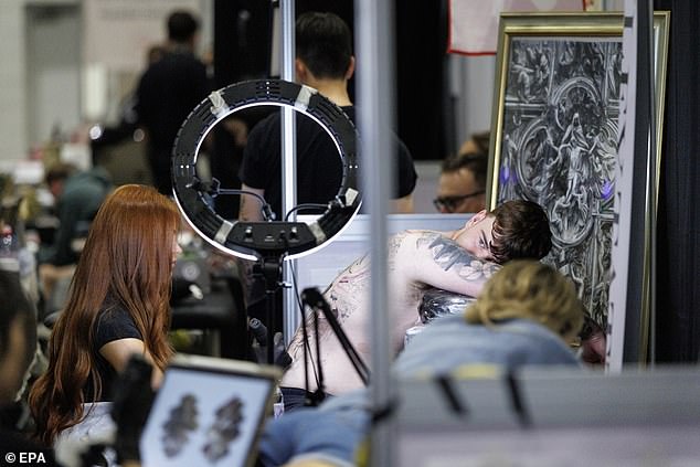 Elsewhere, a visitor is getting a new tattoo from an artist at a booth in the Excel venue