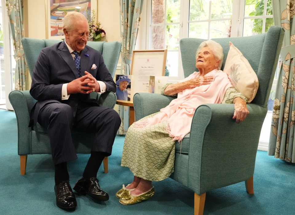 King Charles III laughing while meeting 116-year-old Ethel Caterham.
