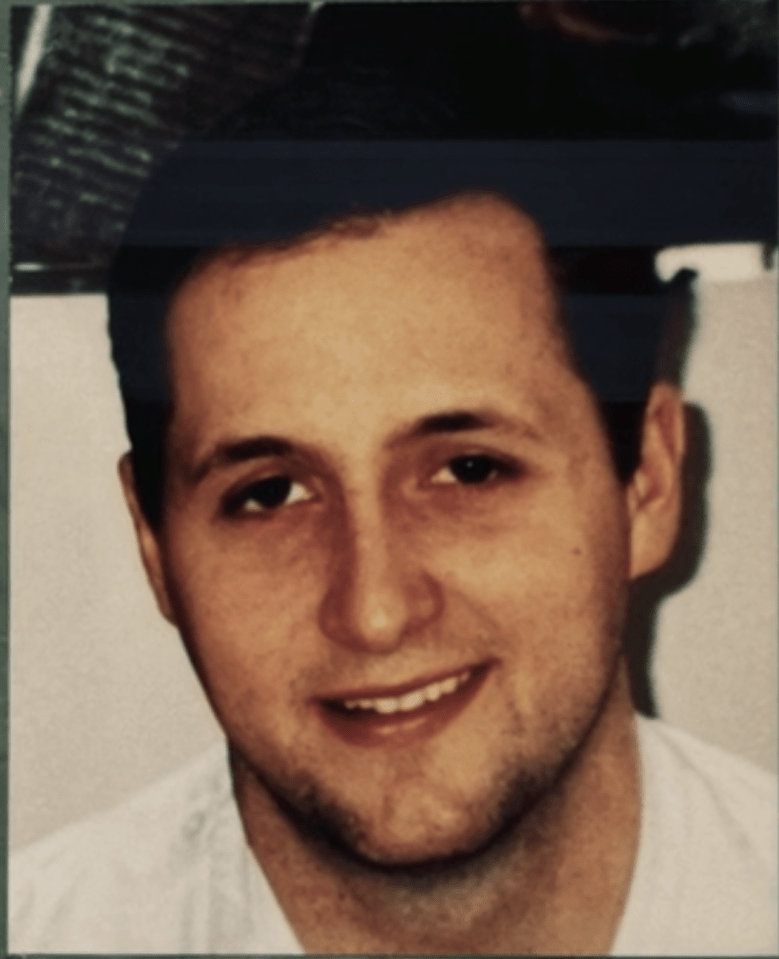 A man with dark hair smiling.