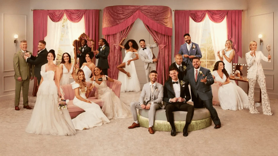 A group of men in suits and women in wedding dresses posing for a picture.