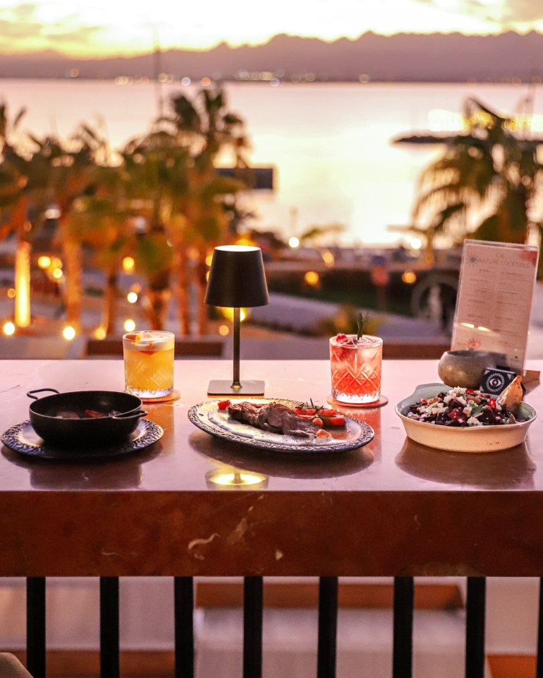 Dinner table with cocktails and sunset view.