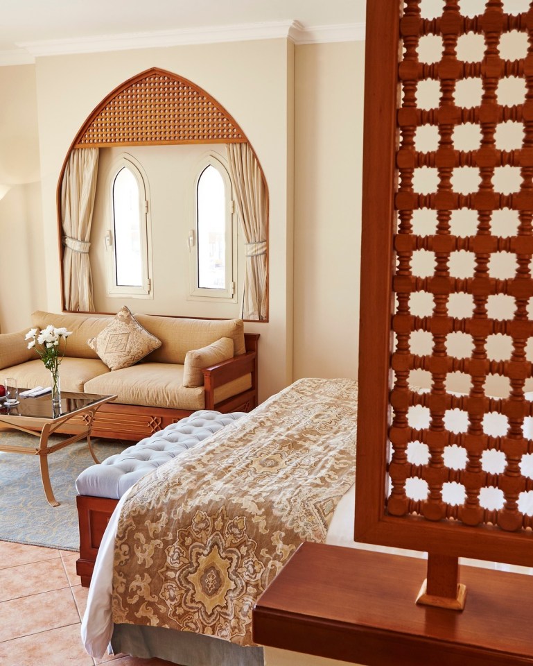 Hotel room with bed, sofa, and ornate wooden details.