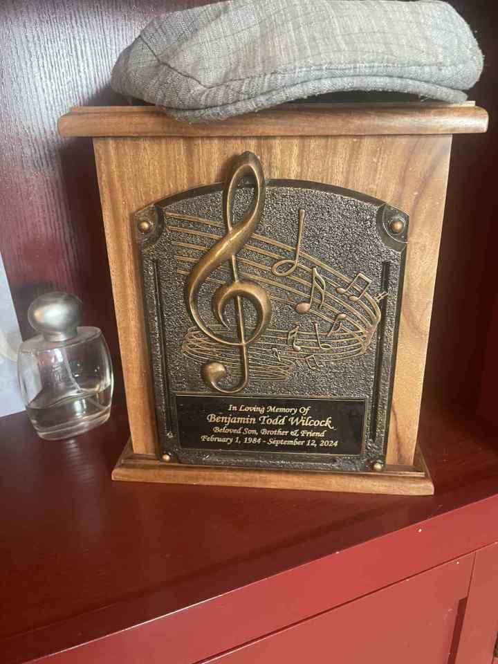 Urn with a brass plaque for Benjamin Todd Wilcock, adorned with a treble clef and musical notes.