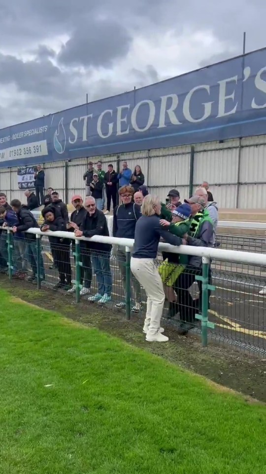 Fans interacting with a player over a barrier at an outdoor sporting event.