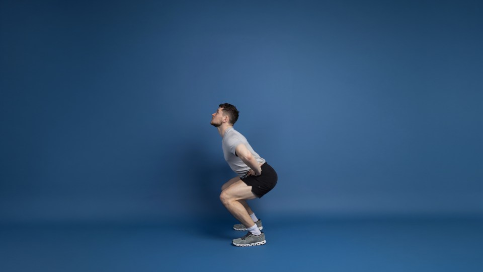 A man in athletic wear performing a squat.
