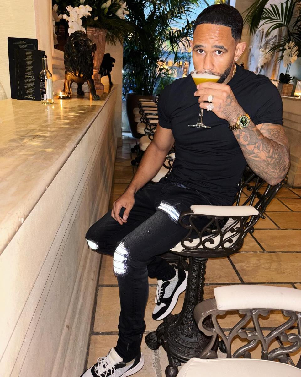 Linton Weirich drinking a cocktail while sitting on a bar stool.