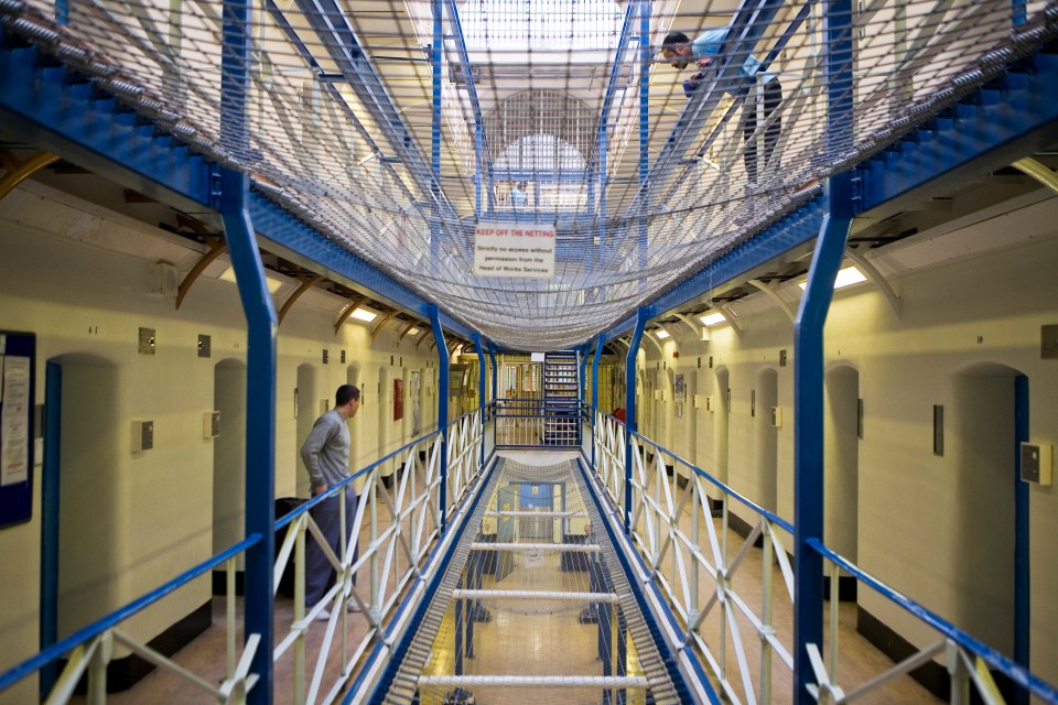 View along a prison wing with suicide netting between floors, showing cells and prisoners.
