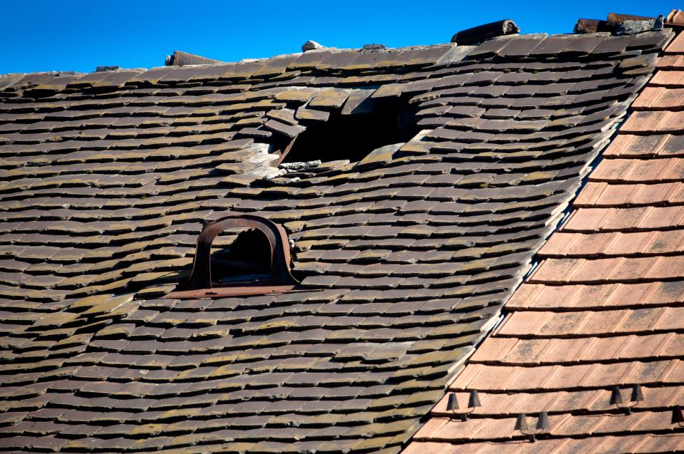 HRXX8J Old damaged tiled roof with broken tiles and a hole on the roof