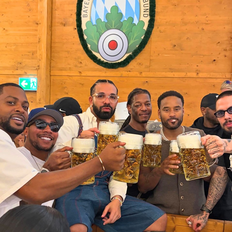 Drake and friends at Oktoberfest holding beer mugs.