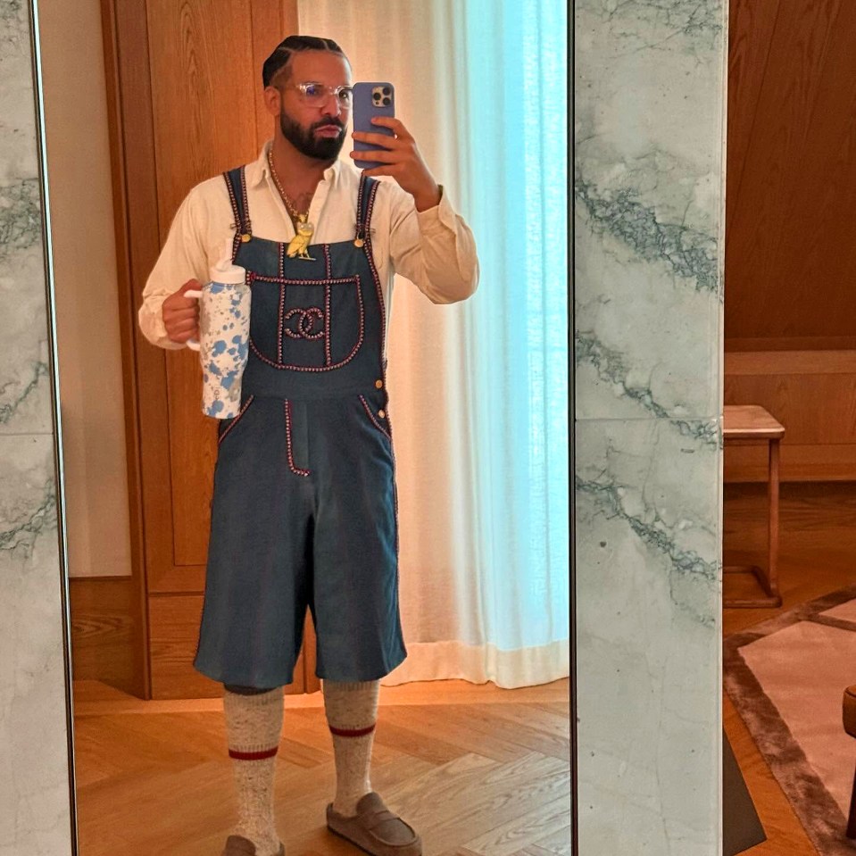 Singer and rapper Drake wearing a German Oktoberfest lederhosen while holding a water bottle and taking a mirror selfie.