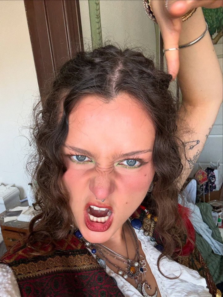 Karin Ann making an angry face at the camera with her arm raised.