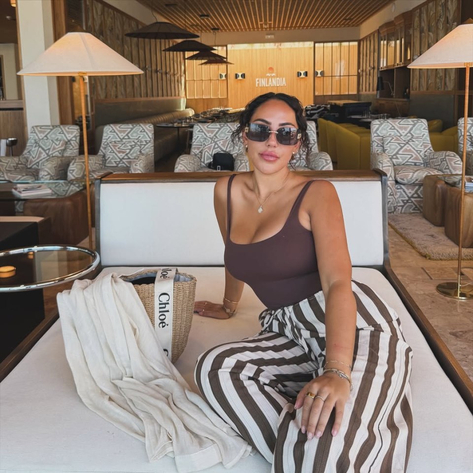 Sophie Kasaei in a brown top and striped pants, sitting in a lounge.