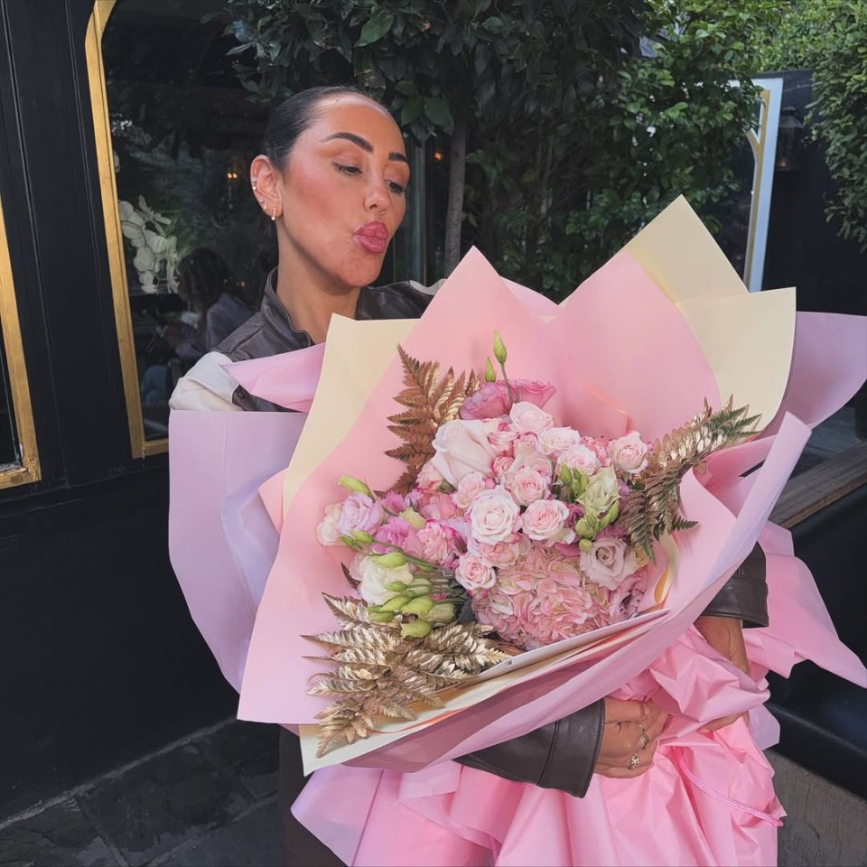 Sophie Kasaei holding a large bouquet of pink and gold flowers.
