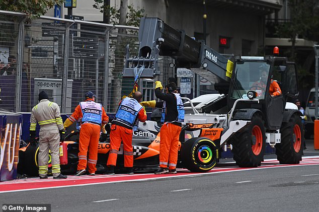 Marshals clear away the car of Oscar Piastri after the Australian crashed again in Baku