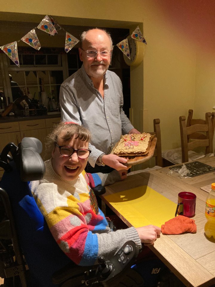 Steve Holbrook-Sishton with his daughter Maddy, who is seated in a wheelchair, holding a cake with a "35" candle on it.