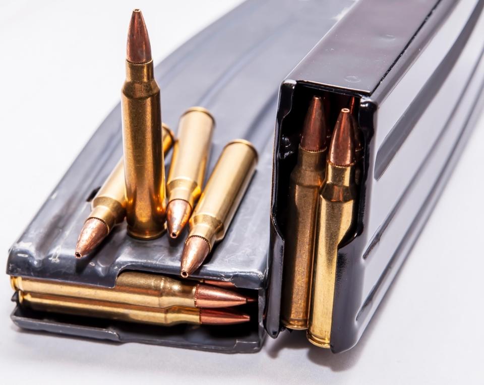 Two loaded rifle magazines with 223 caliber bullets around them.