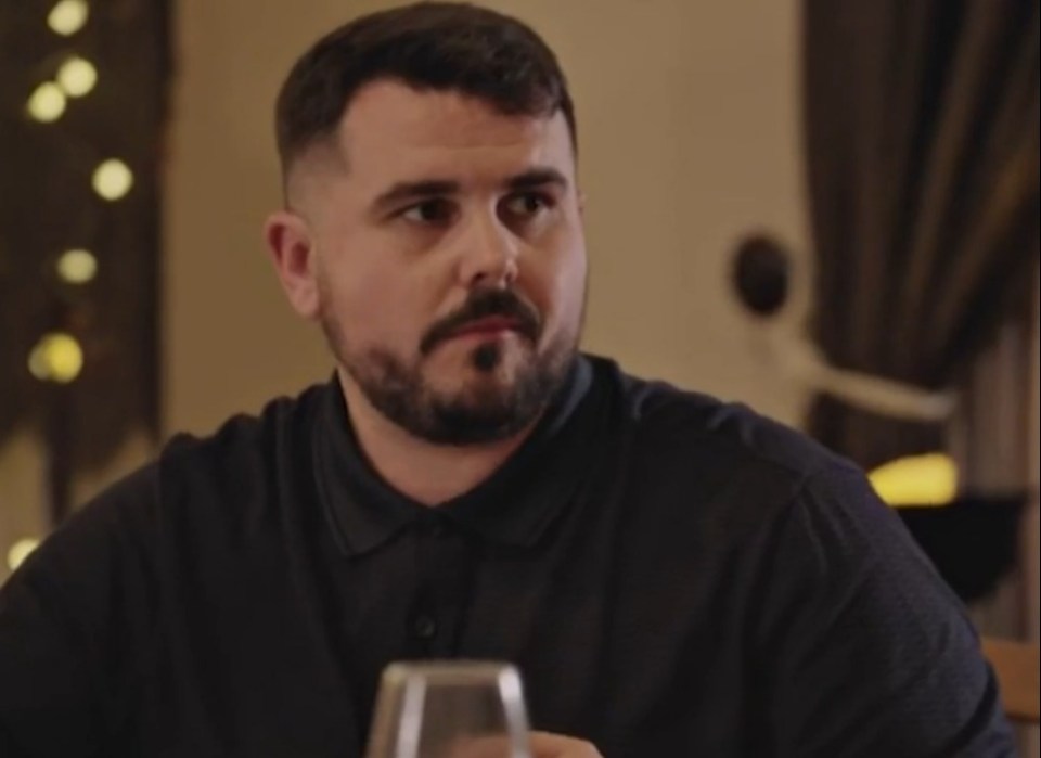 A man with a beard and dark polo shirt looking to the right.