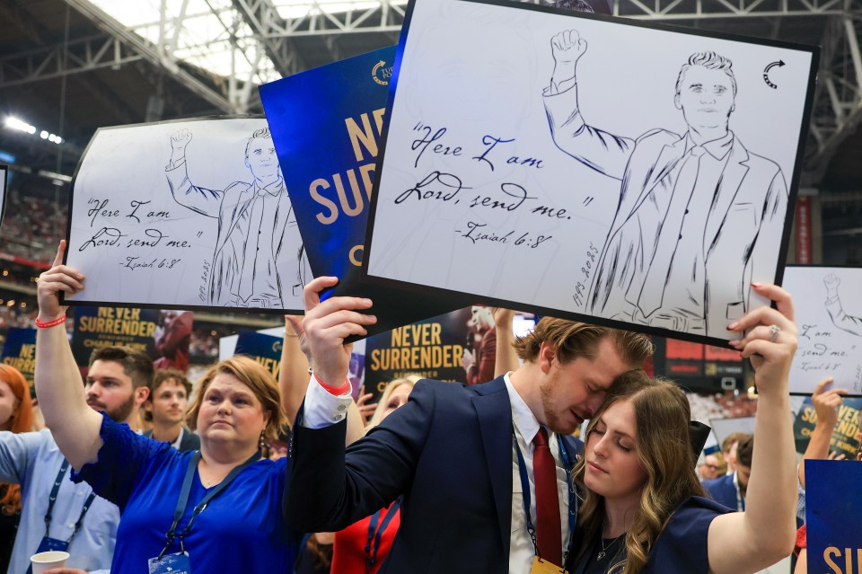 Attendees hold up signs at the memorial service for political activist Charlie Kirk at State Farm Stadium.