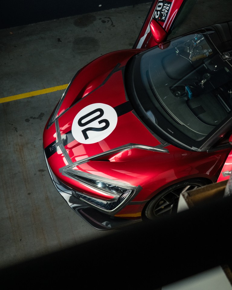 Overhead view of the red Yangwang U9 Xtreme production car, with "02" on the hood, parked indoors.