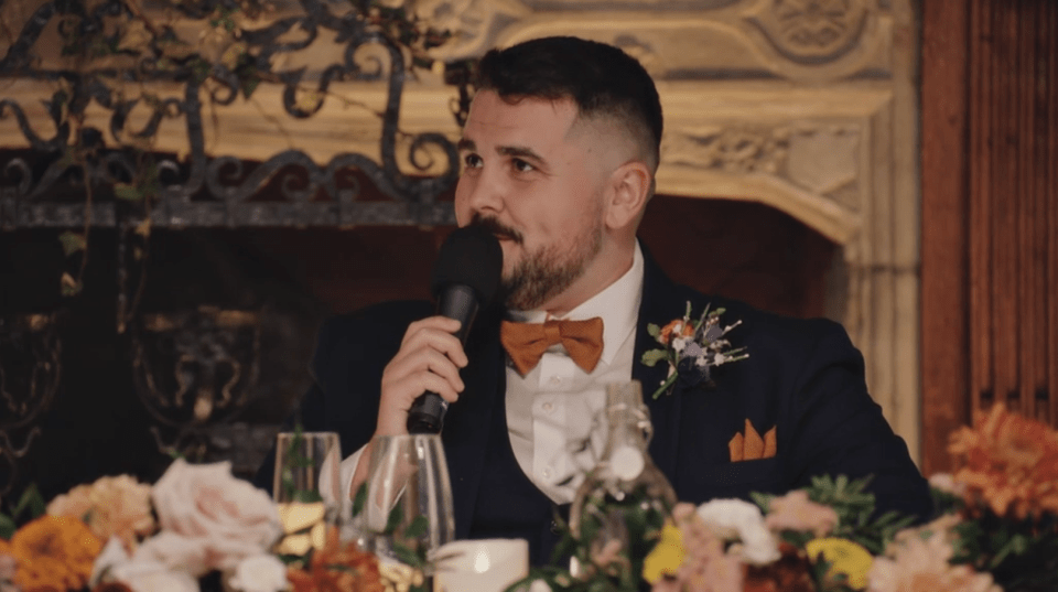 A man in a suit giving a speech with a microphone.