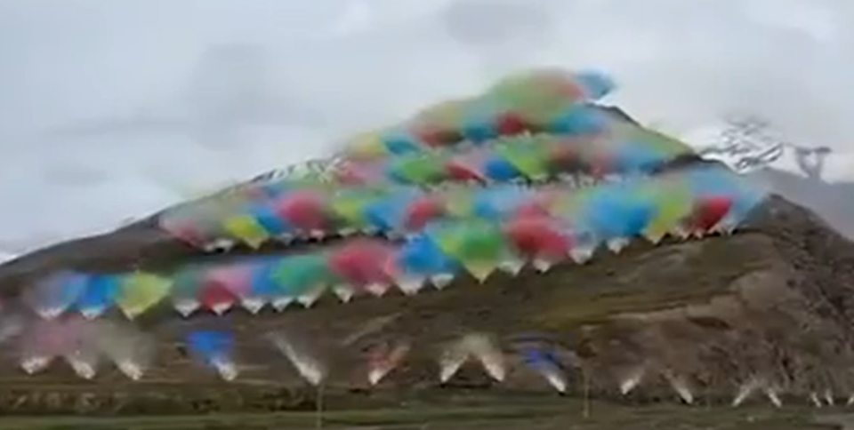 A mountain covered in vibrant fireworks smoke against a cloudy sky.