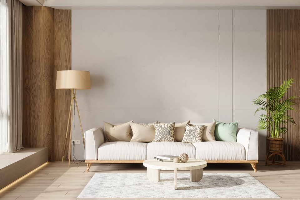 Illustration of a modern living room interior with a white sofa, floor lamp, potted plant, coffee table, and blank wall.
