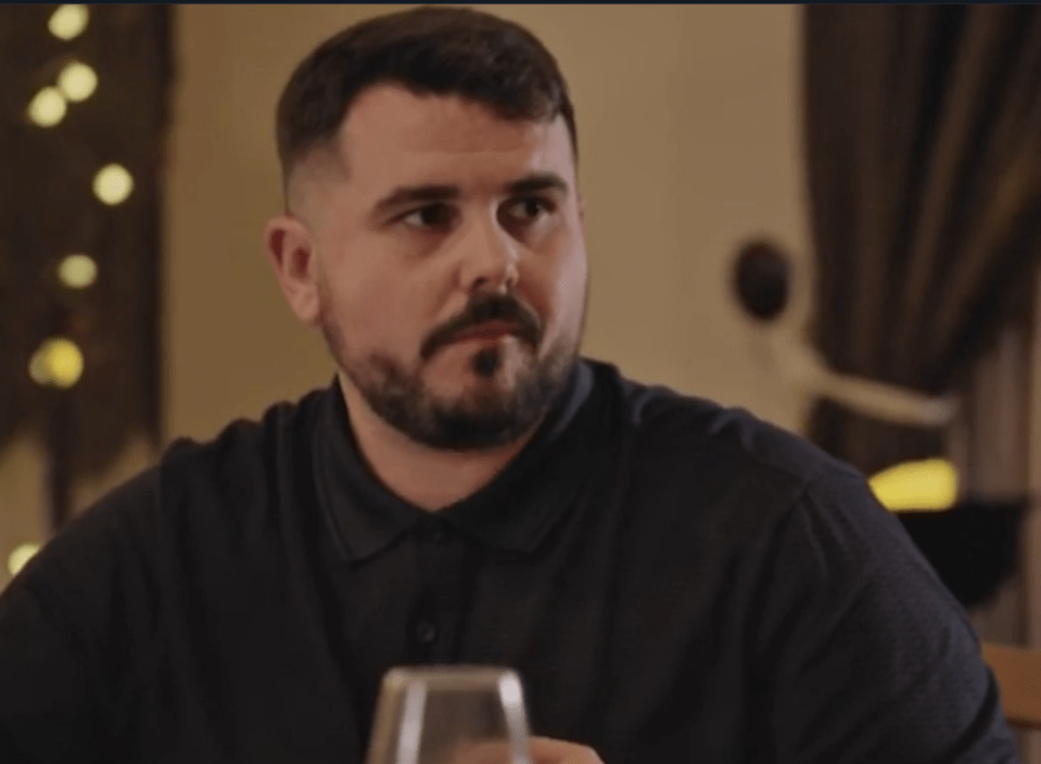 A man with a beard and dark polo shirt looking to the right.