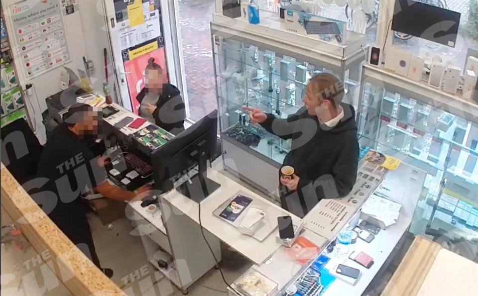 Muzz Bruckner and another man in a black hoodie talking to a woman behind the counter in a store.