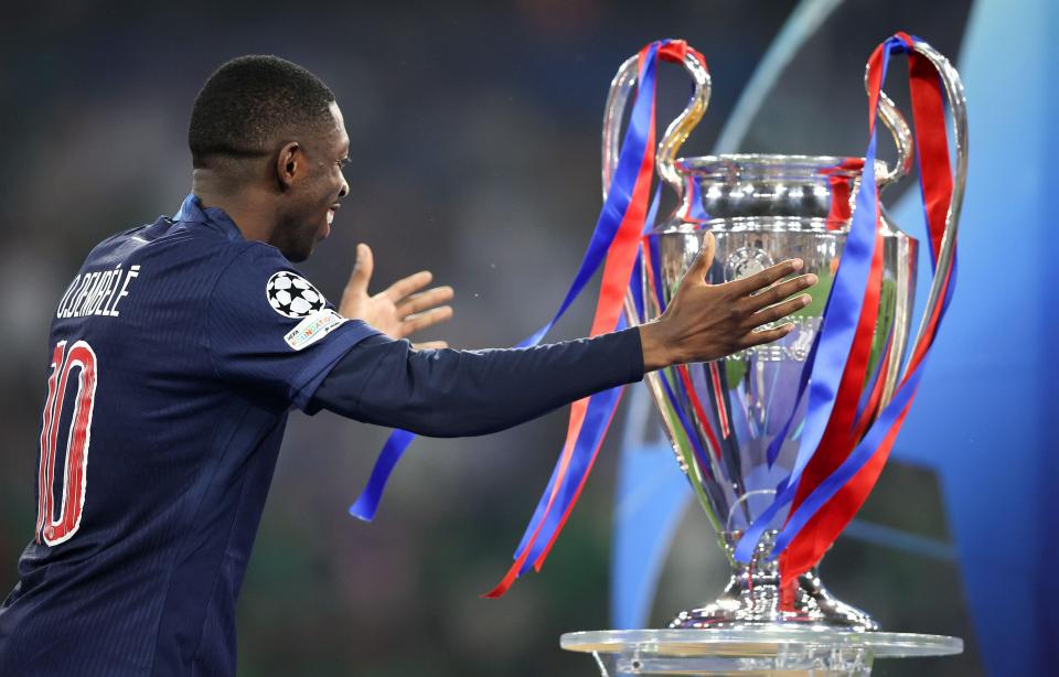 Ousmane Dembélé reaching out towards the UEFA Champions League trophy.