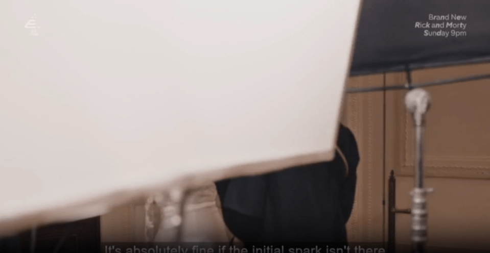 A television screen showing a partially obscured scene with a white object in the foreground, a person in dark clothing, and a light stand, with "Brand New Rick and Morty Sunday 9pm" and "It's absolutely fine if the initial spark isn't there" text overlays.